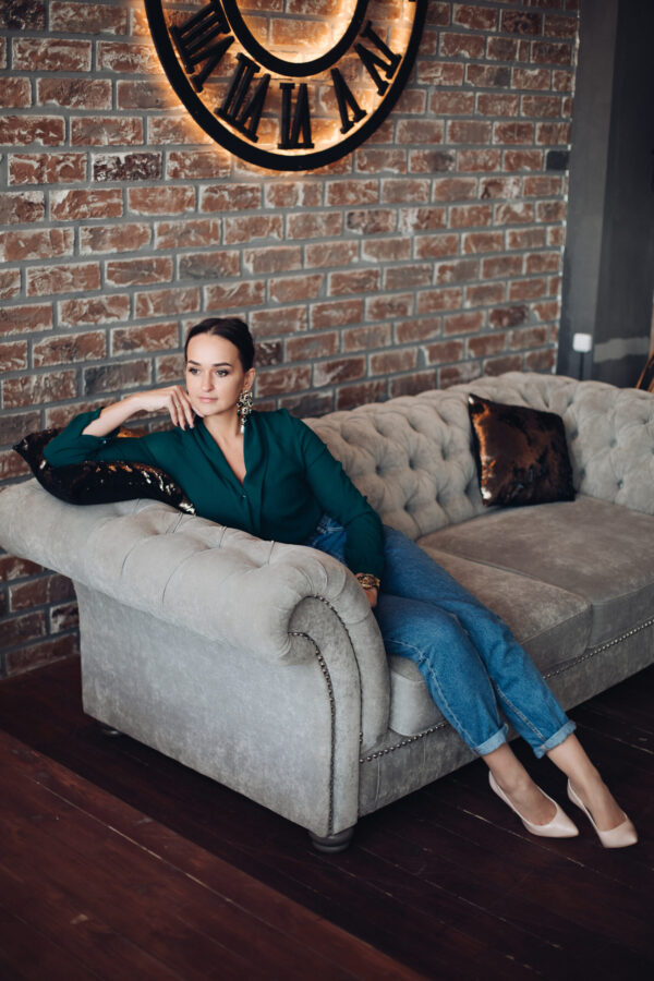 Elegant young woman sitting on sofa in loft apartment.