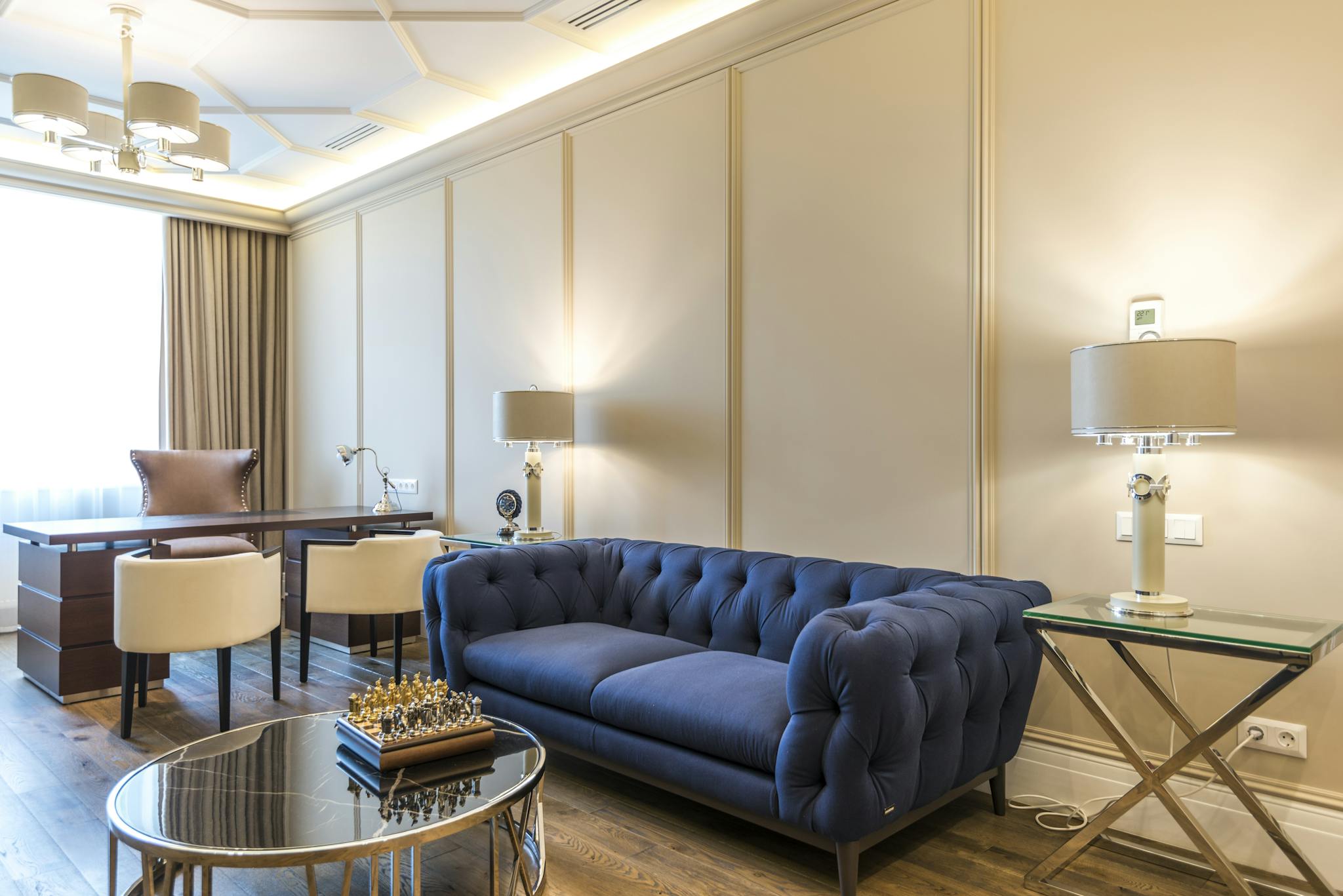 A stylish interior with modern furniture, featuring a chic blue sofa and elegant desk setup.