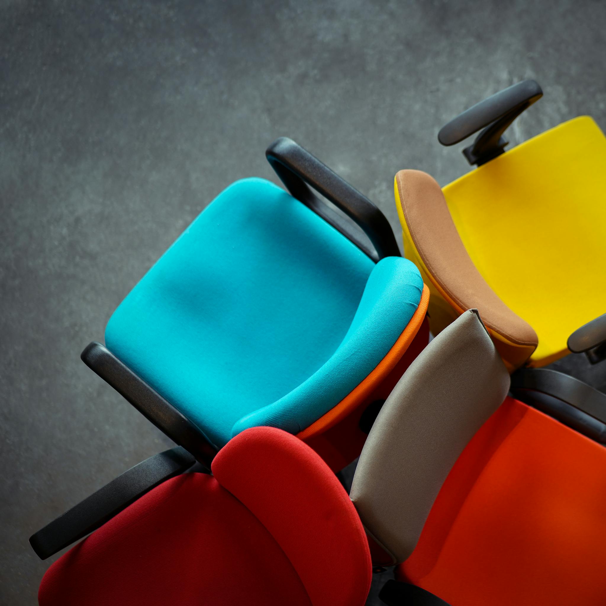 A vibrant collection of multi-colored office chairs viewed from above, showcasing modern design.