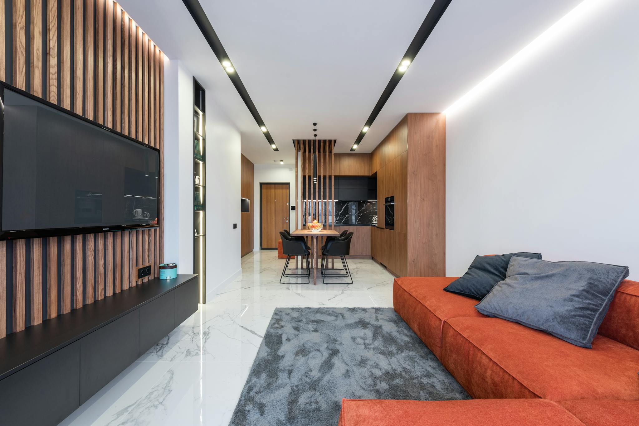 Interior of studio apartment with comfortable sofa and TV and dining table in kitchen area
